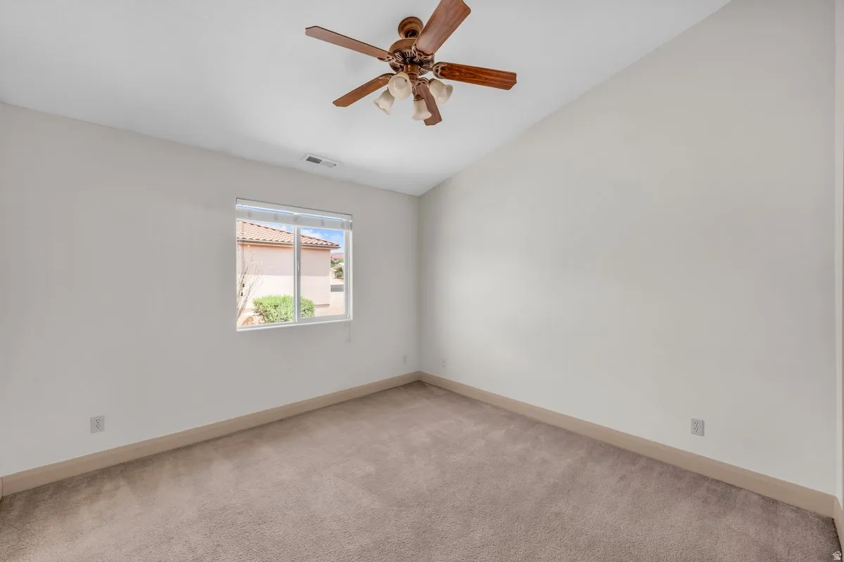 Carpeted room featuring a ceiling fan with light kit, a window with horizontal blinds, and neutral wall tones