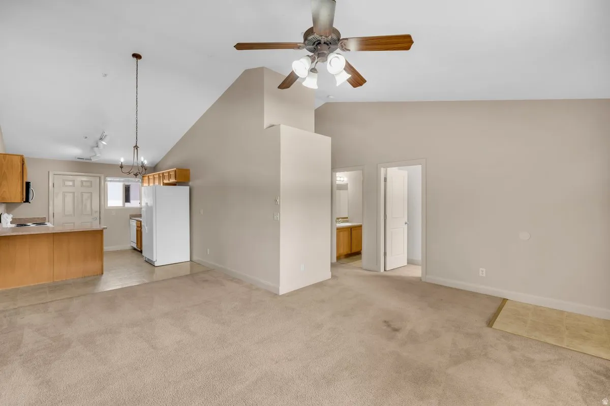 Open-concept living area featuring a vaulted ceiling with a ceiling fan, recessed lighting, and neutral carpet flooring