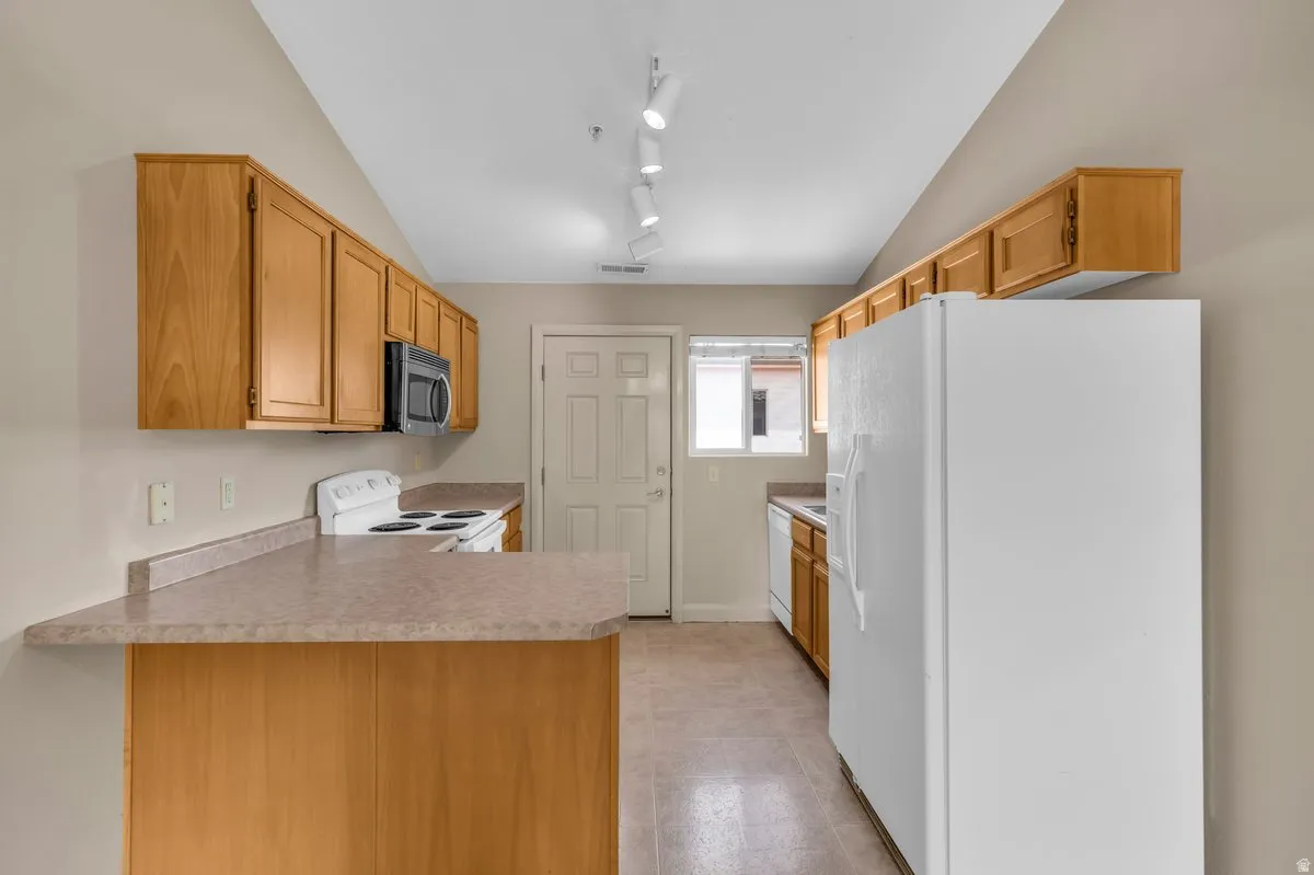 Kitchen featuring wood-finish cabinetry, a light-toned countertop, and track lighting