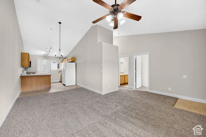 Vaulted ceiling with a ceiling fan, recessed lighting, and a chandelier