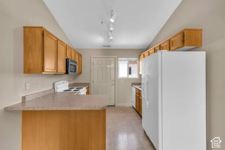 Kitchen featuring wood-finish cabinetry, track lighting, and a white refrigerator