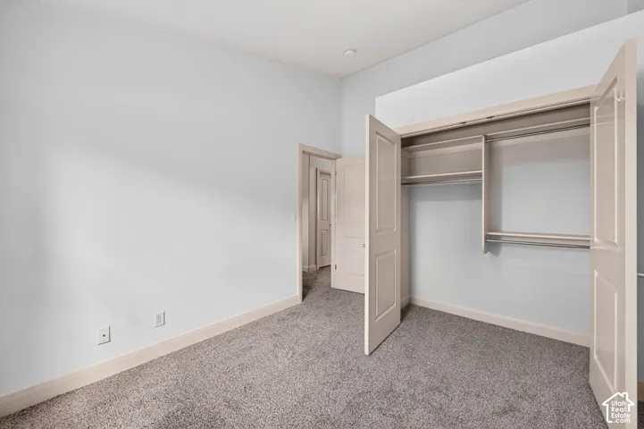 Carpeted room with a built-in closet featuring bi-fold doors and shelving