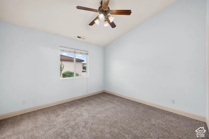 Vaulted ceiling with a ceiling fan, light-colored wall paint, and wall-to-wall carpeting