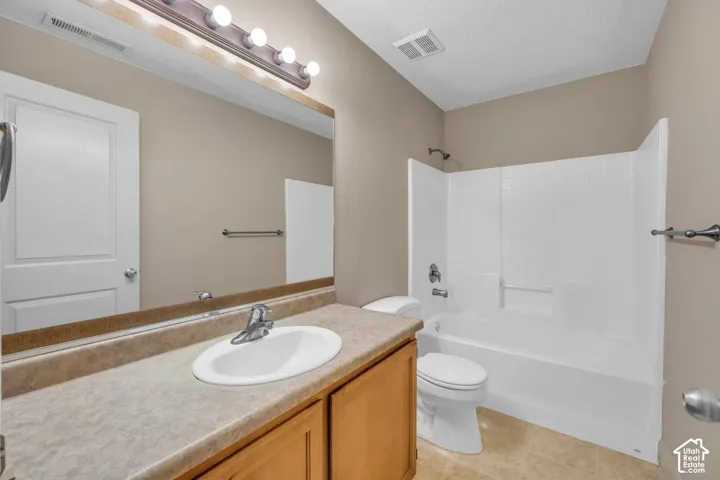 Bathroom featuring a vanity with a drop-in sink, a built-in tub with a shower, and tile flooring