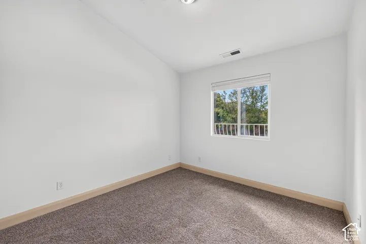 Carpeted flooring with light wood trim, a single window with blinds, and white painted walls