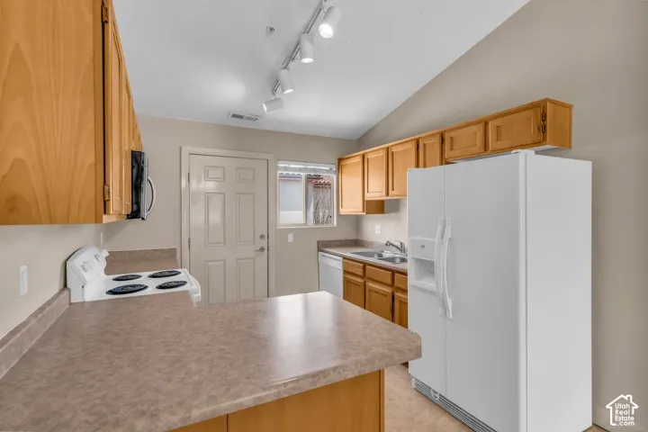 Kitchen featuring wood-finish cabinetry, track lighting, a white electric range, a double basin sink, and laminate countertops