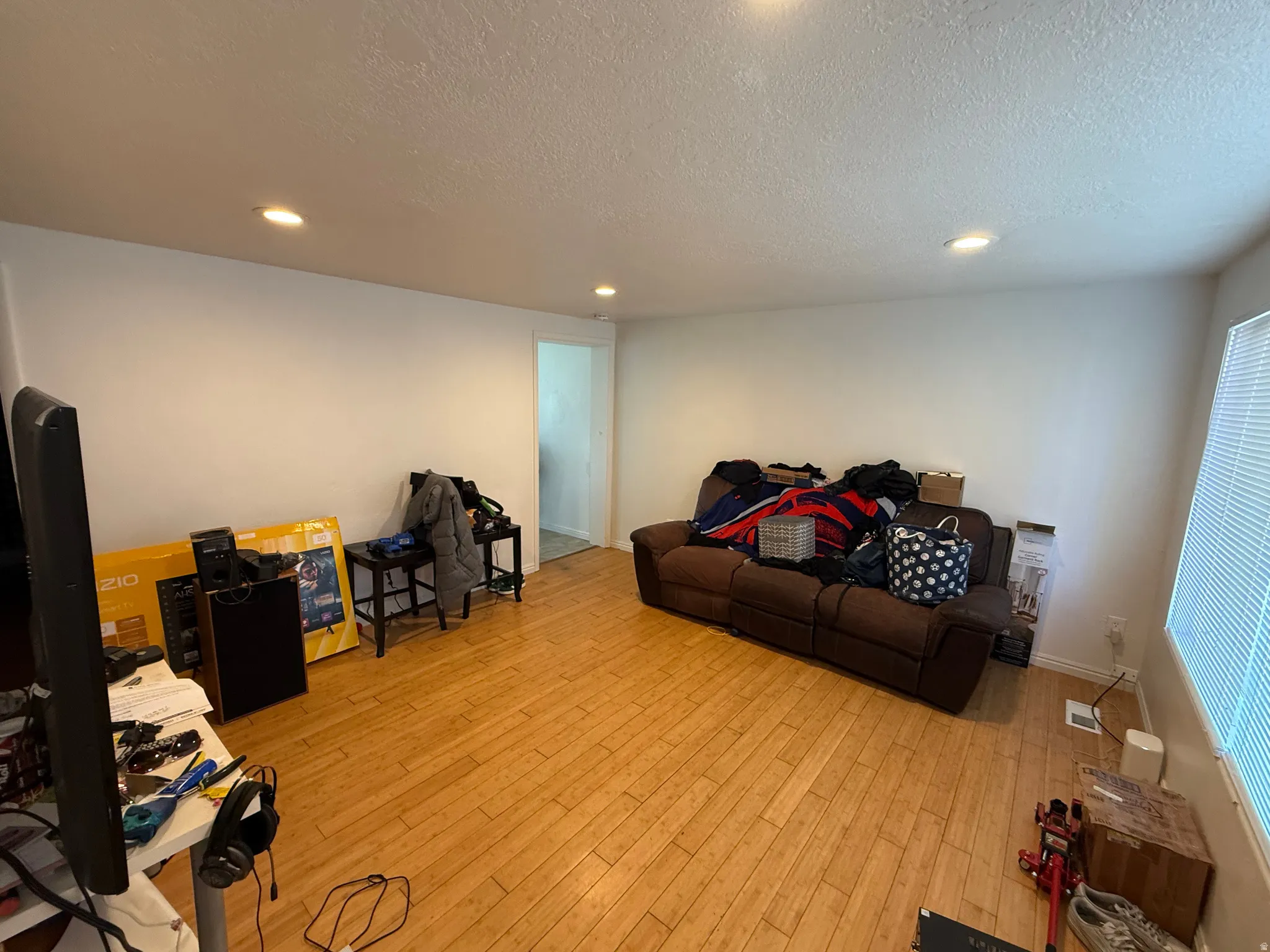 Living area featuring a textured ceiling, light wood-style floors, and recessed lighting