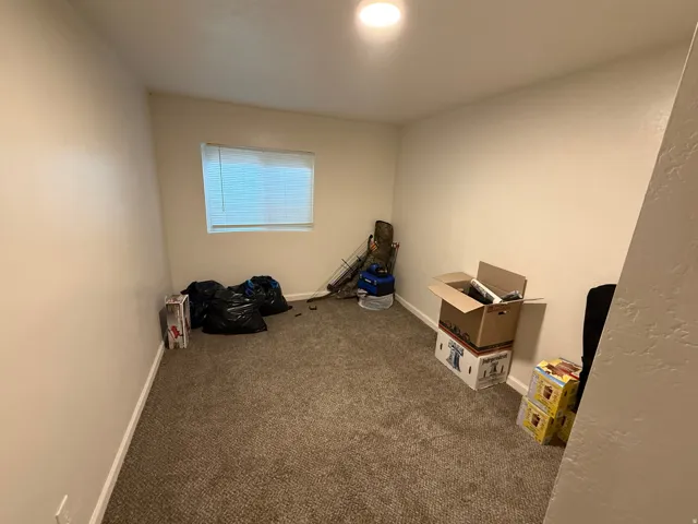 Misc room with dark colored carpet and baseboards