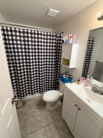 Bathroom with vanity, a textured ceiling, and a shower with curtain
