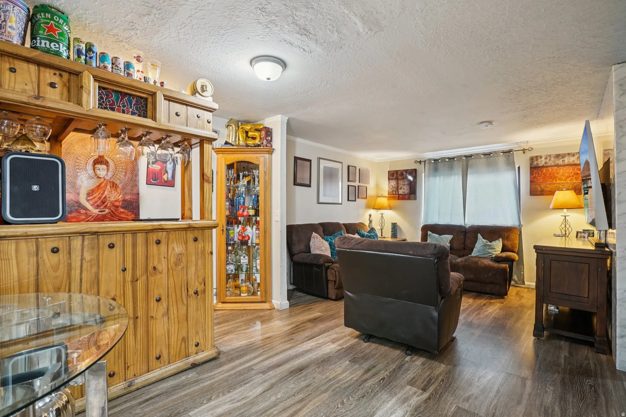 Living room featuring wood finished floors, a textured ceiling, and crown molding