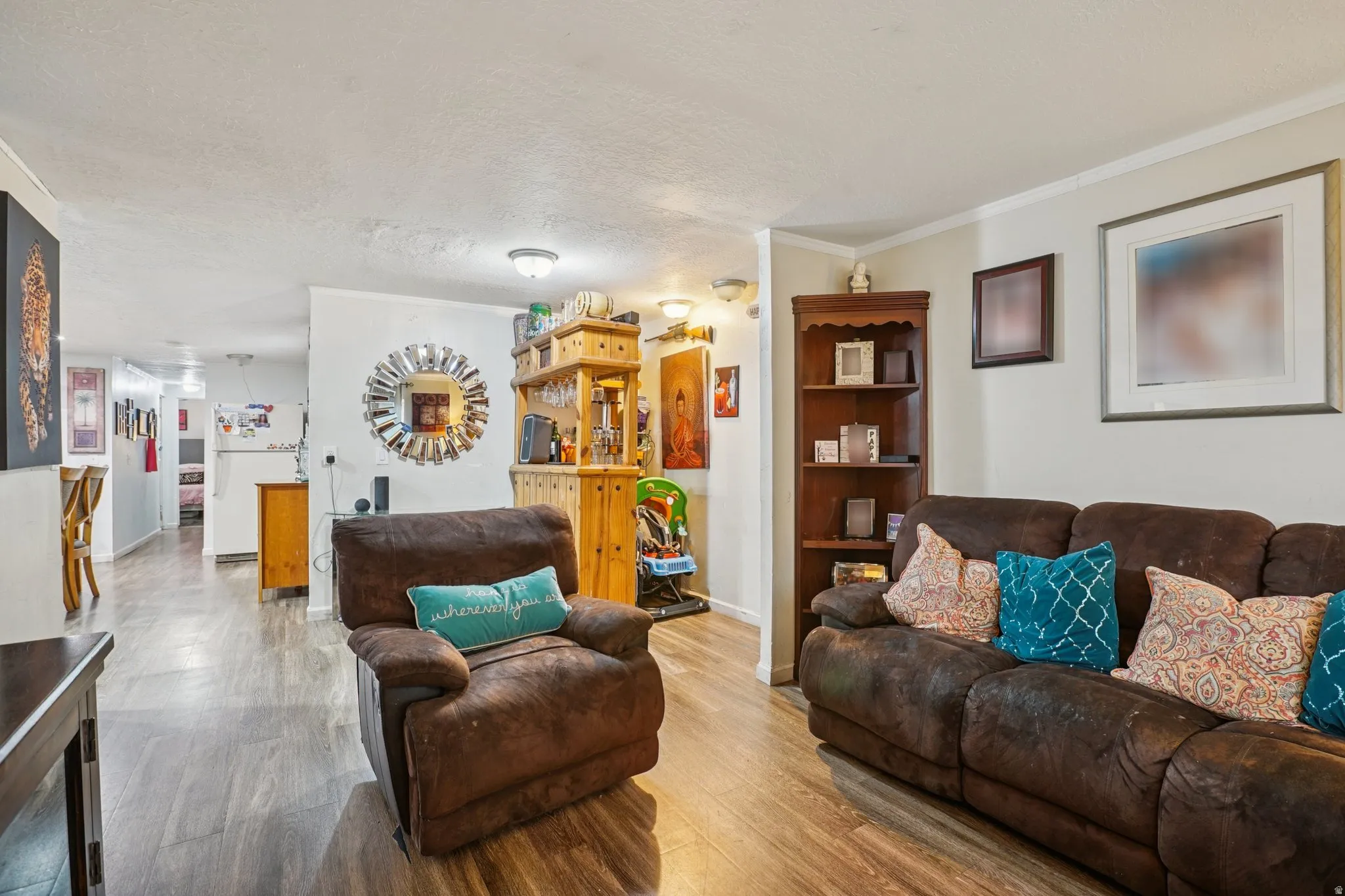 Living room featuring a textured ceiling, crown molding, and wood finished floors