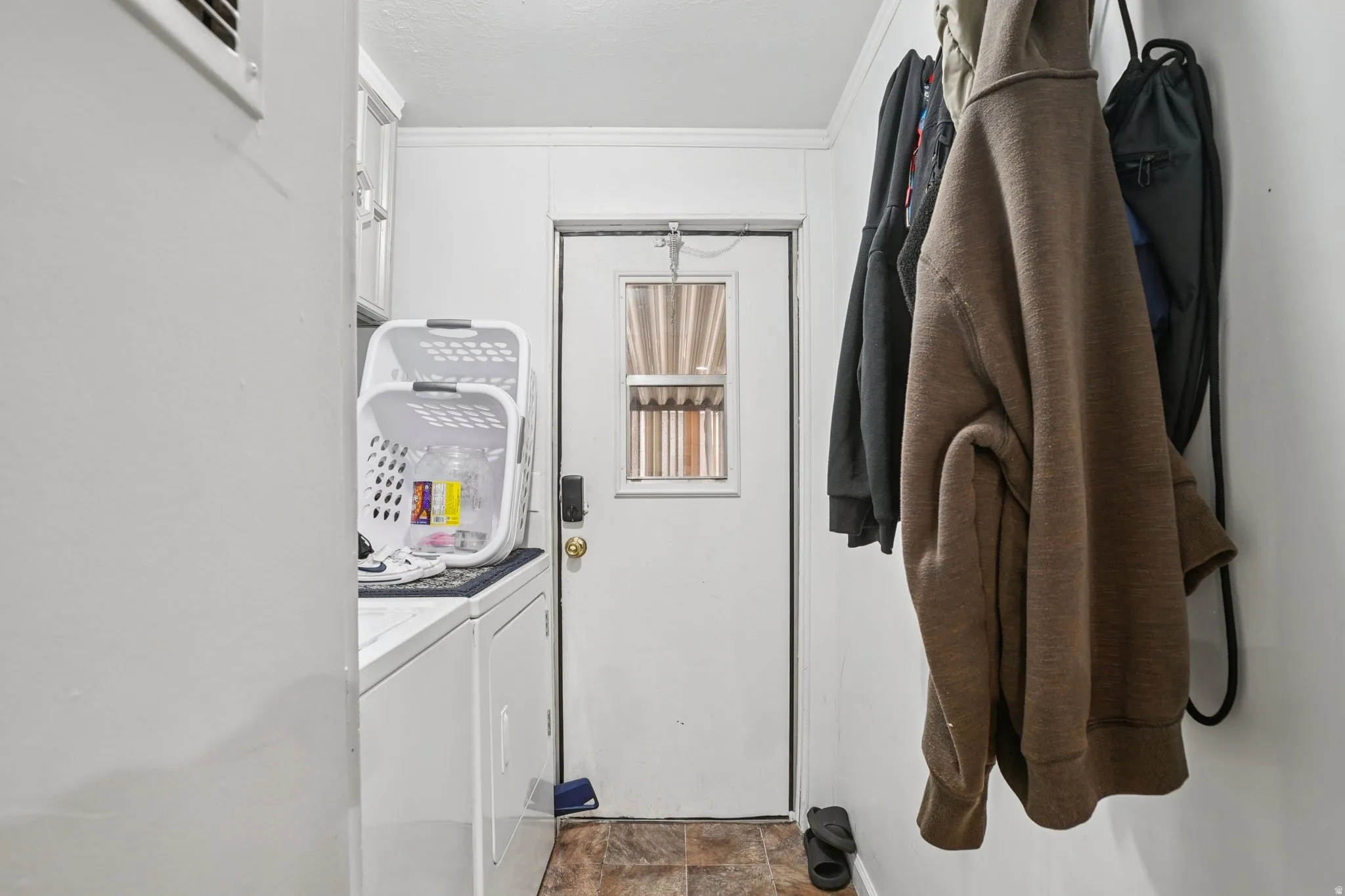 Laundry area with washing machine and dryer, stone finish flooring, and crown molding