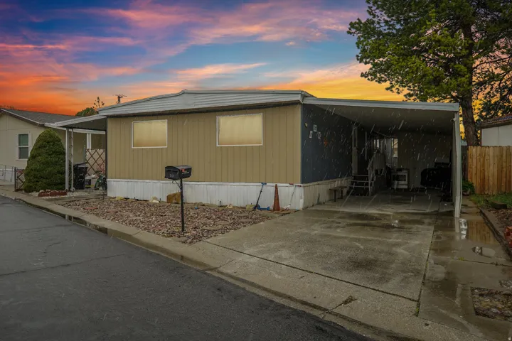 View of side of property with a carport, concrete driveway, and a patio