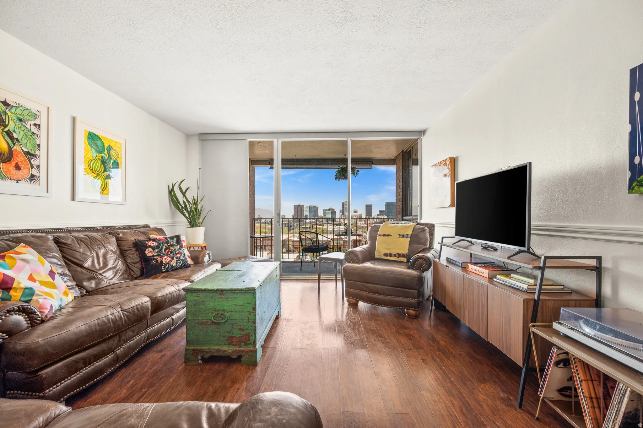 Living room with expansive windows, dark wood-style floors, and a textured ceiling
