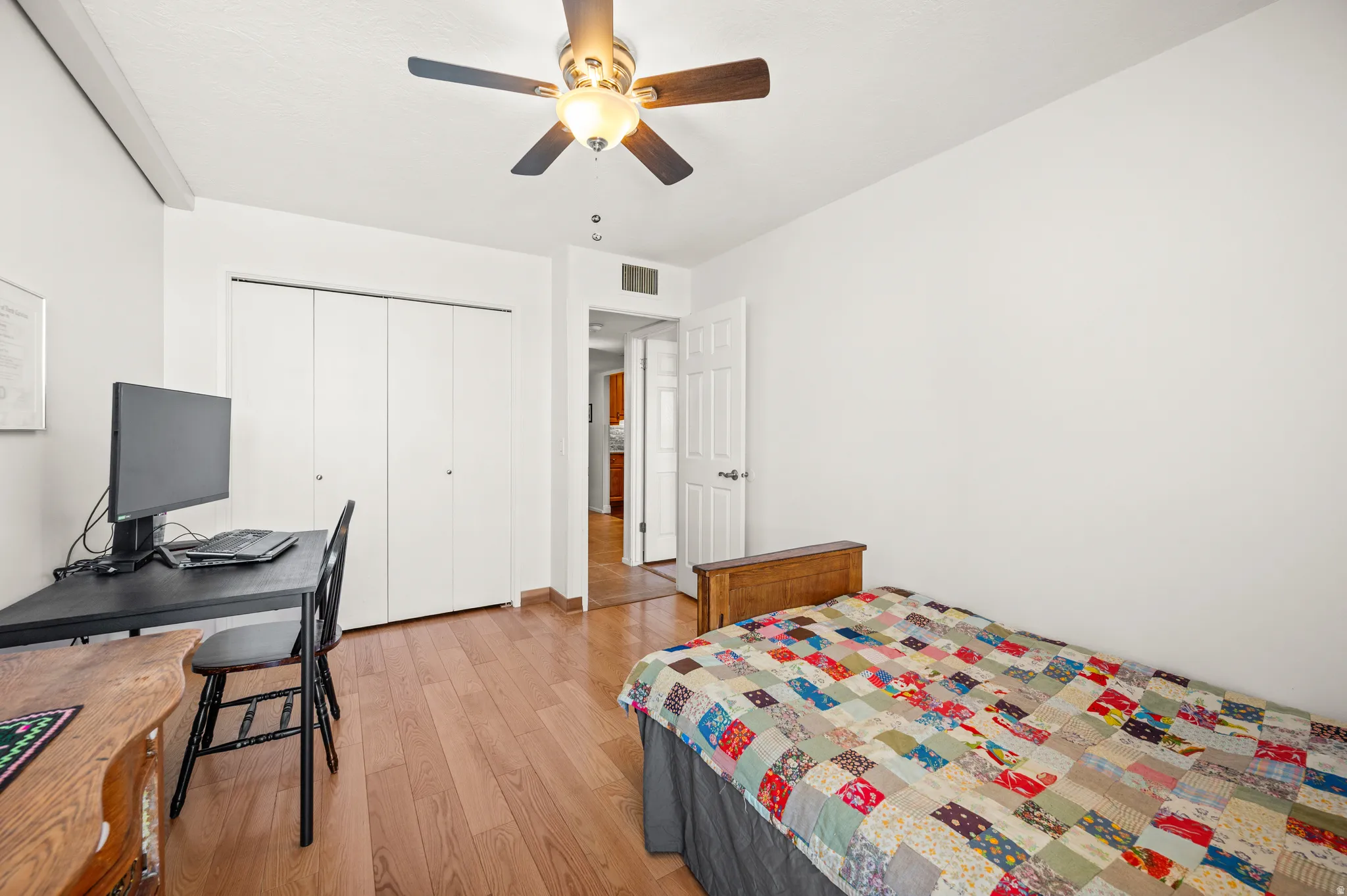 Bedroom with light wood-style flooring, ceiling fan, a closet, and a desk