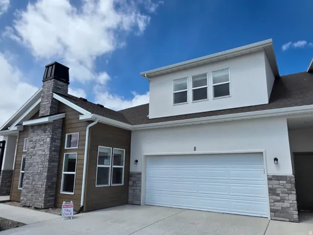 View of front of home with stone siding, stucco siding, concrete driveway, and a garage