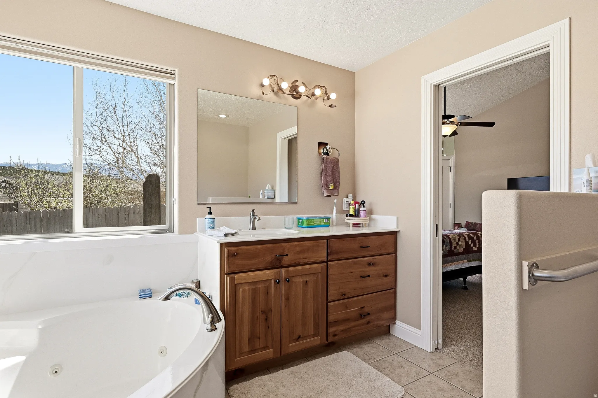Bathroom with ensuite bathroom, vanity, a whirlpool tub, light tile patterned floors, and ceiling fan