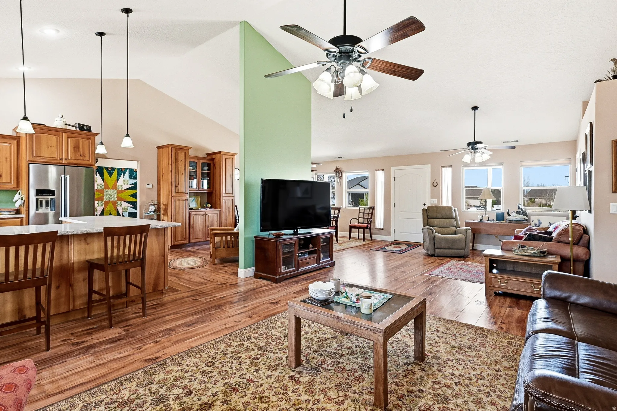 Living room featuring dark wood-type flooring, vaulted ceiling, and ceiling fan