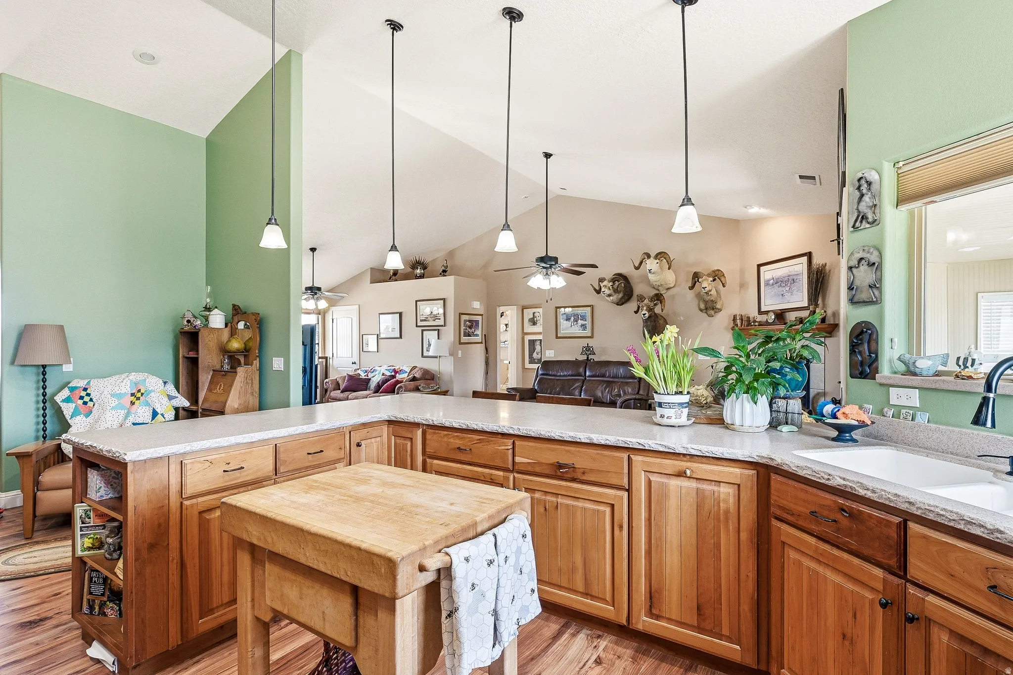 Kitchen featuring light stone countertops, light wood-type flooring, open floor plan, wood finish cabinets, and a high ceiling