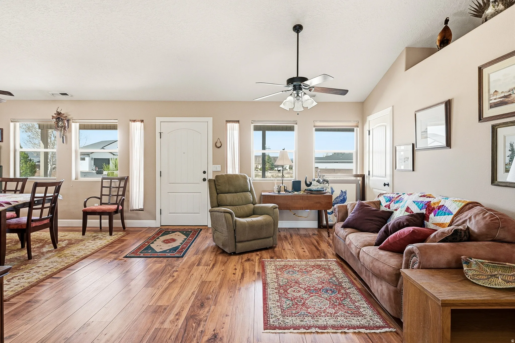 Living area with a ceiling fan, hardwood / wood-style floors, and lofted ceiling