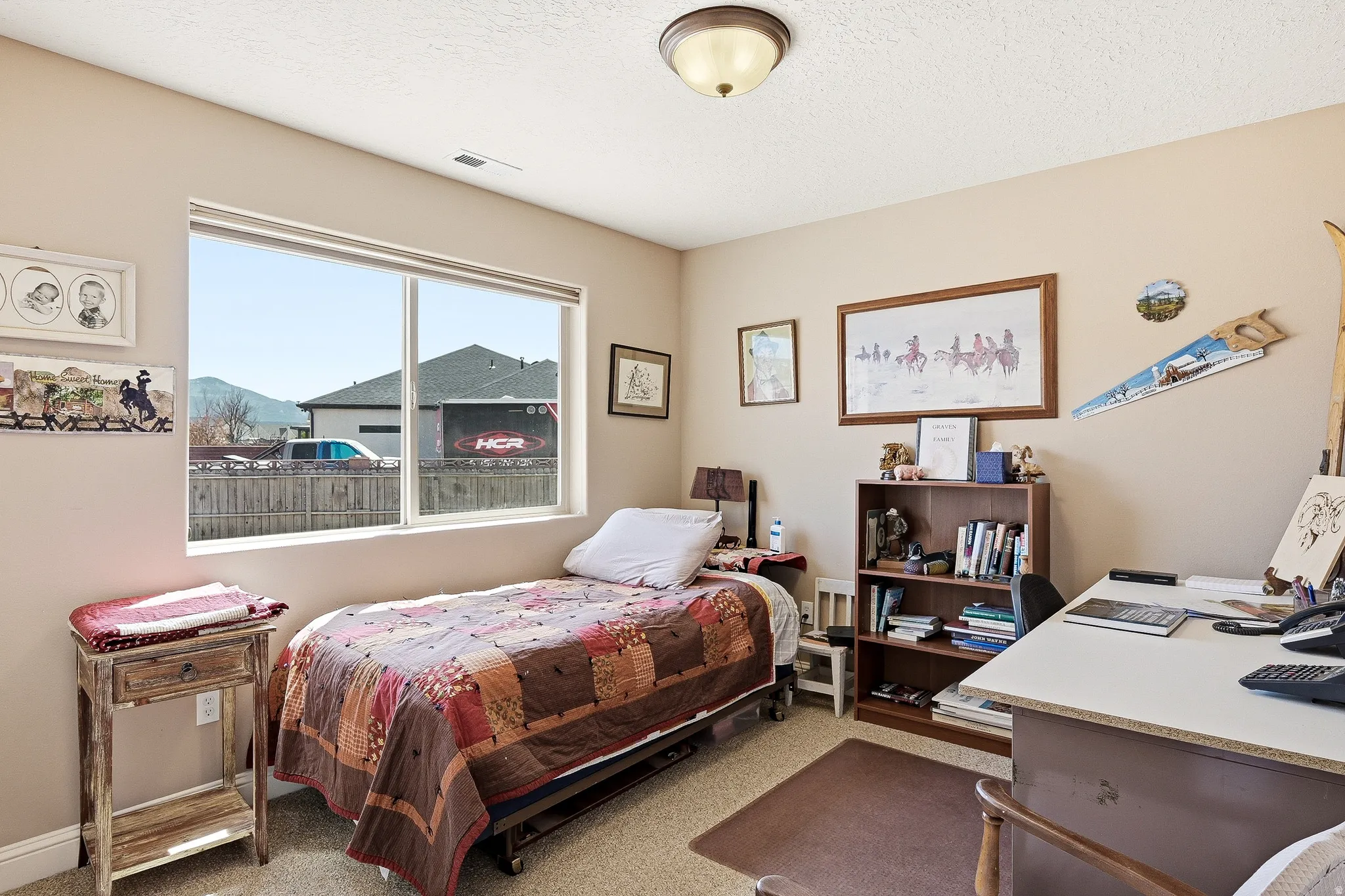 Bedroom with light colored carpet and a desk