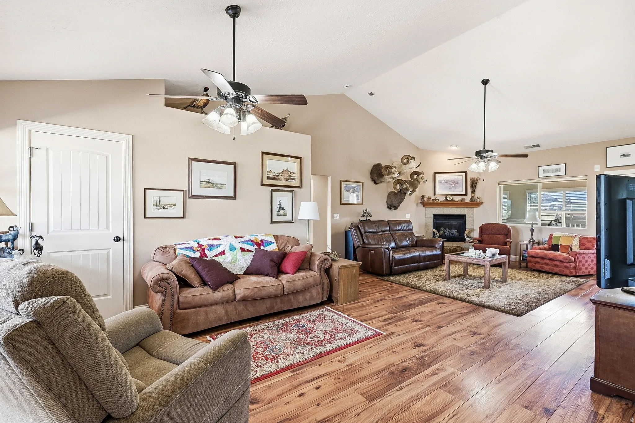 Living area with ceiling fan, hardwood / wood-style floors, a fireplace, and a high ceiling
