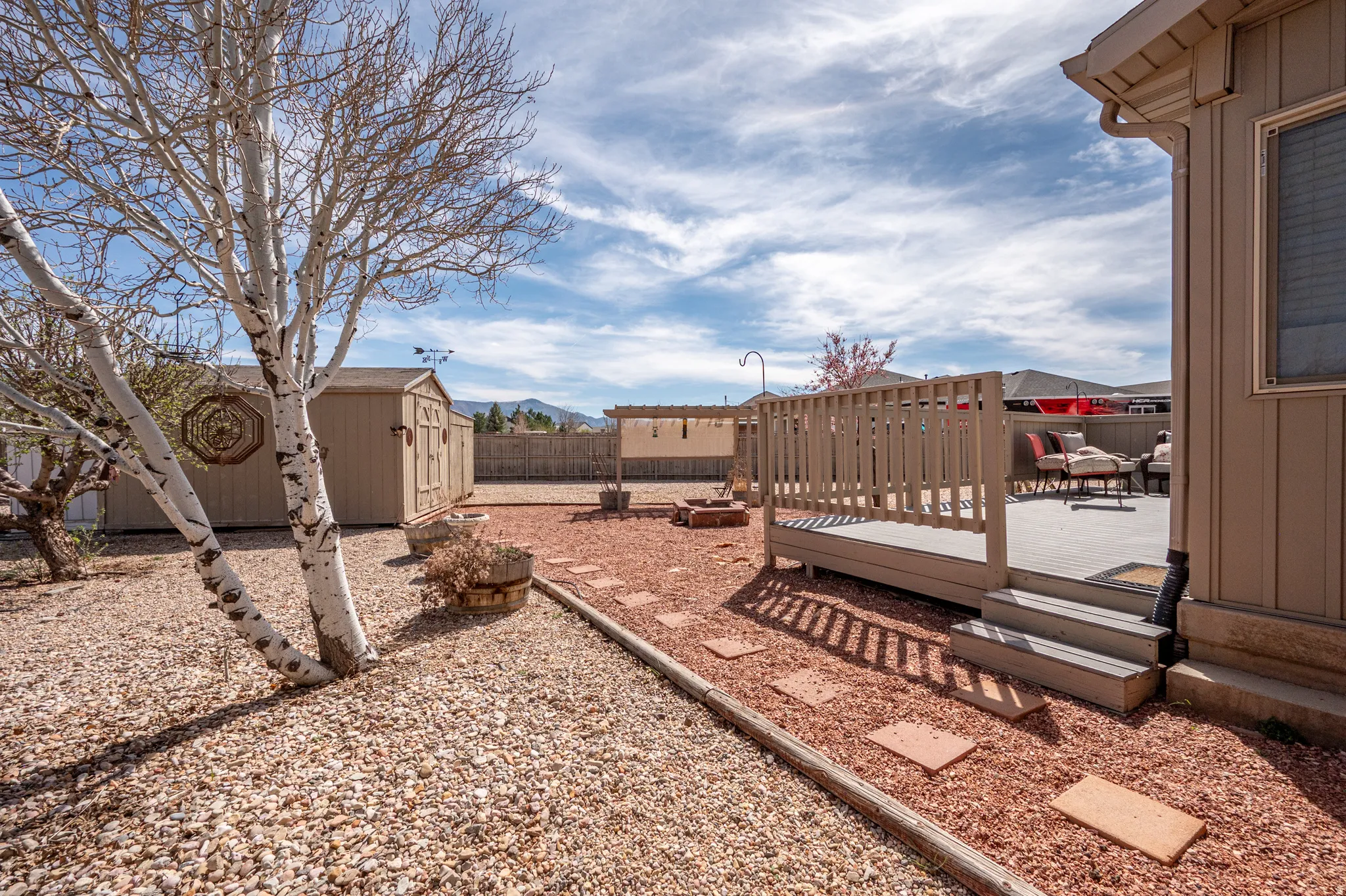 Fenced backyard featuring a wooden deck and a storage unit