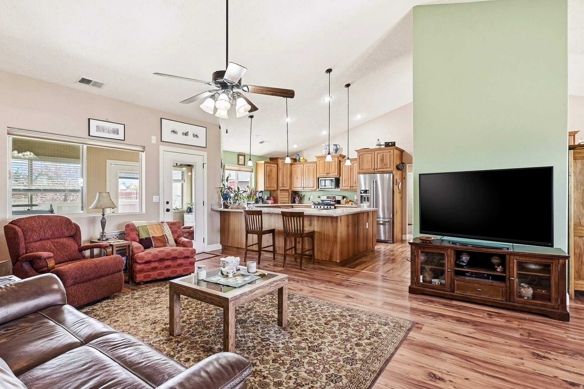 Living room with ceiling fan, light wood-type flooring, lofted ceiling, and recessed lighting