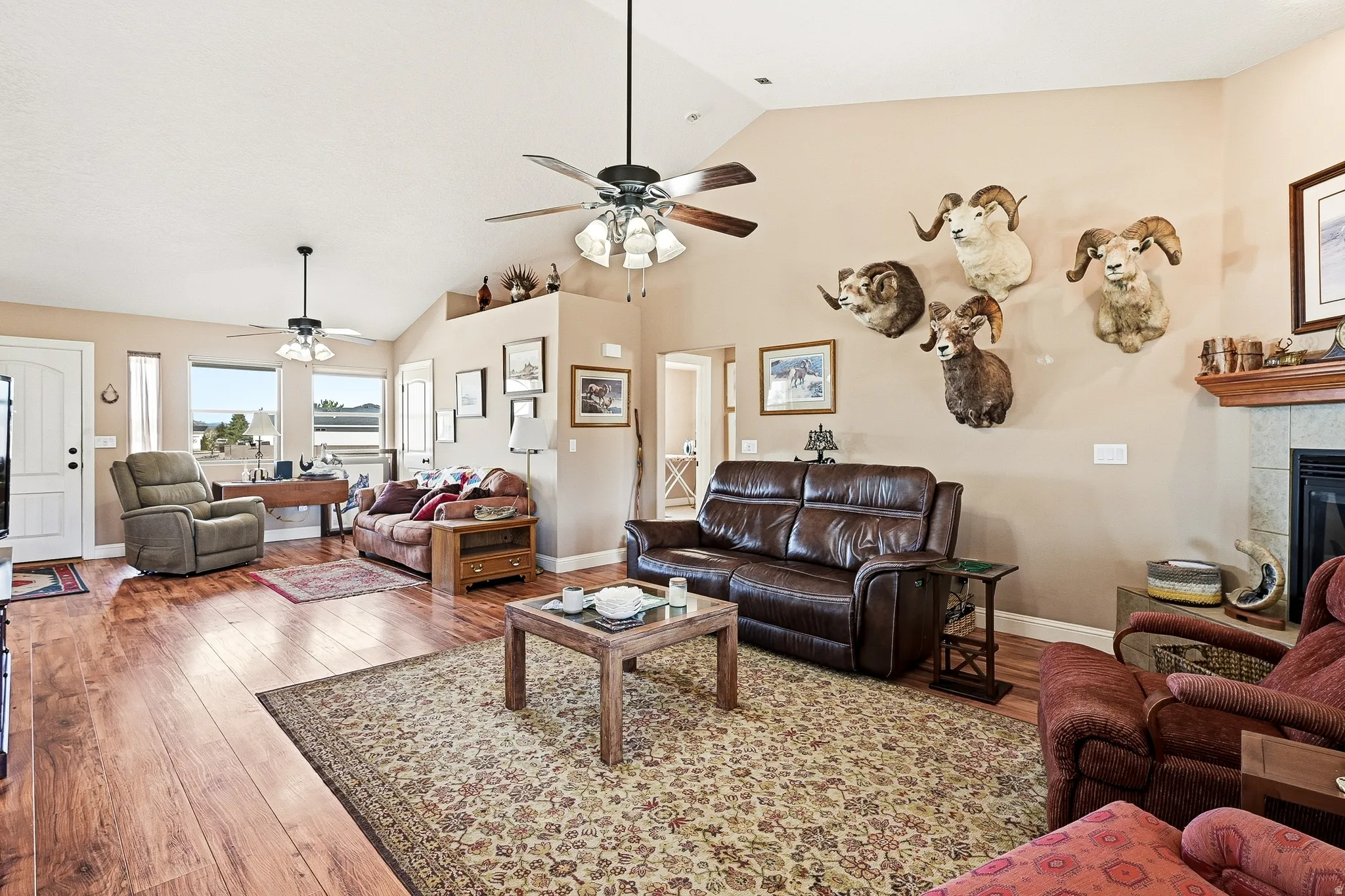 Living room with lofted ceiling, light wood-style flooring, a fireplace, and ceiling fan