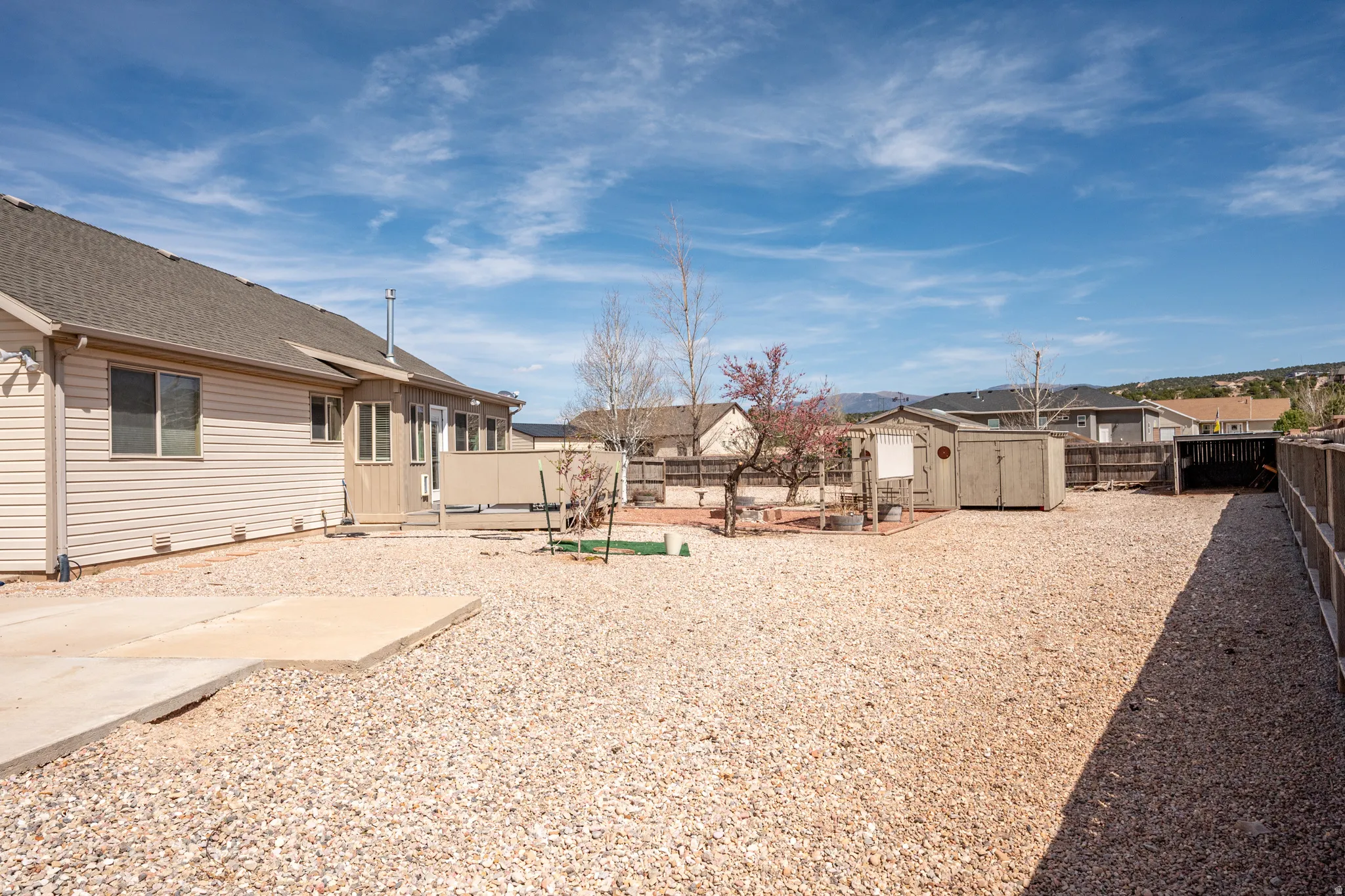 Fenced backyard with a patio, a shed, and a residential view