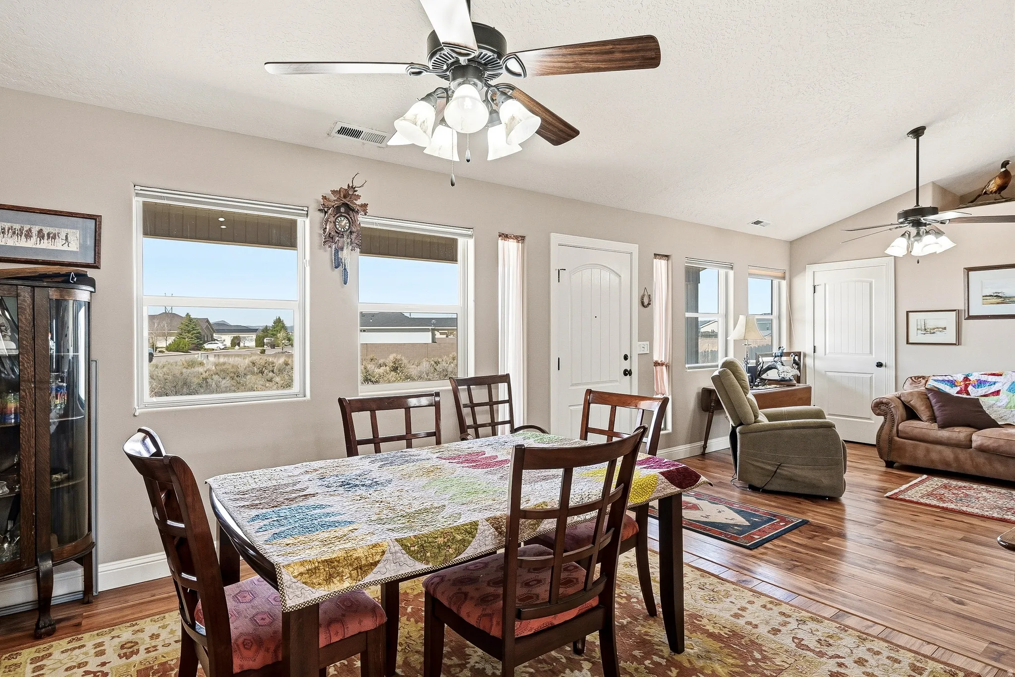 Dining room featuring ceiling fan, wood-type flooring, and vaulted ceiling