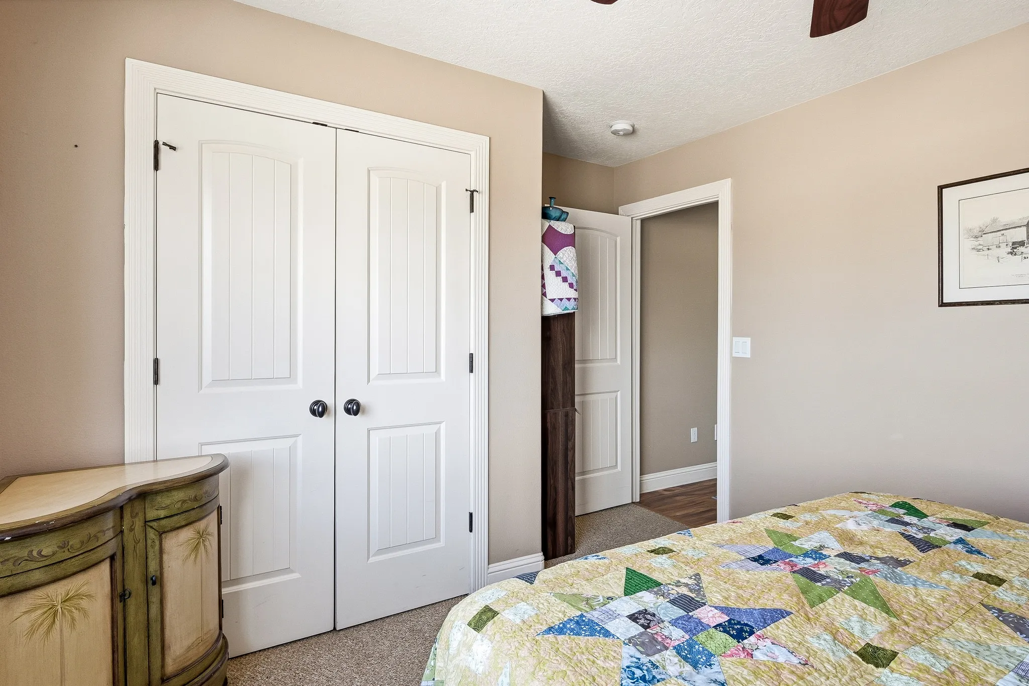 Bedroom with a closet, a ceiling fan, a textured ceiling, and dark colored carpet