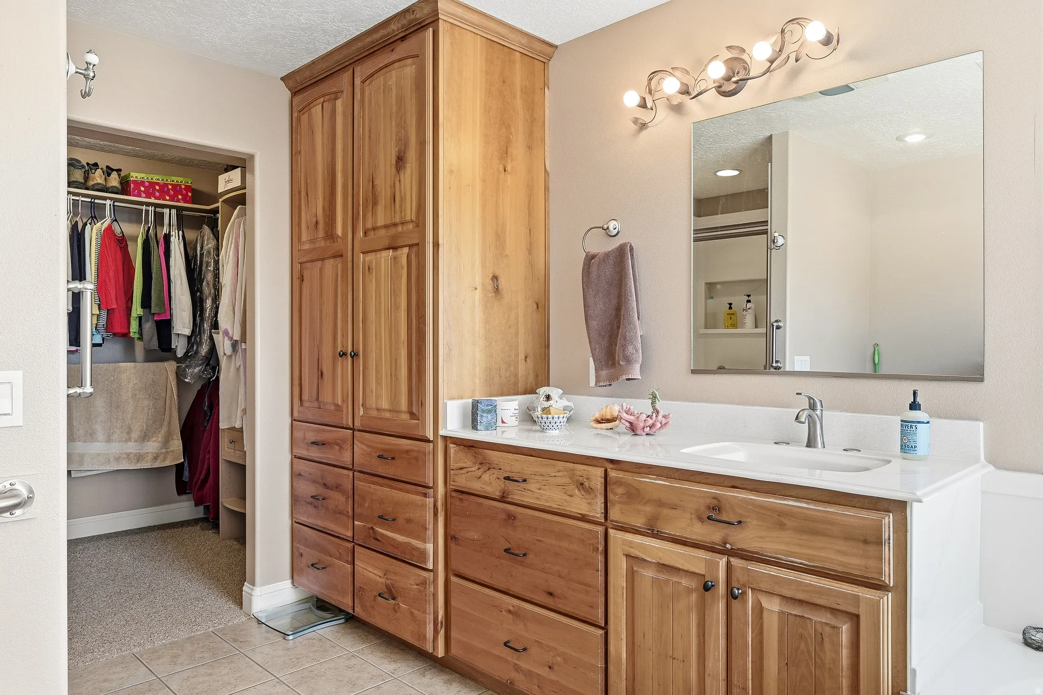 Full bathroom with a spacious closet, vanity, a stall shower, a textured ceiling, and light tile patterned floors