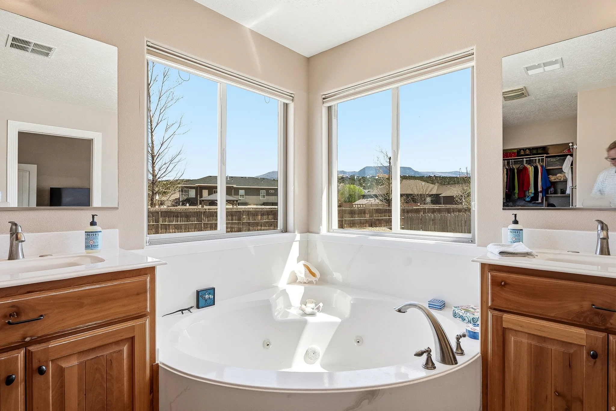 Bathroom featuring two vanities, a jetted tub, a residential view, and a mountain view