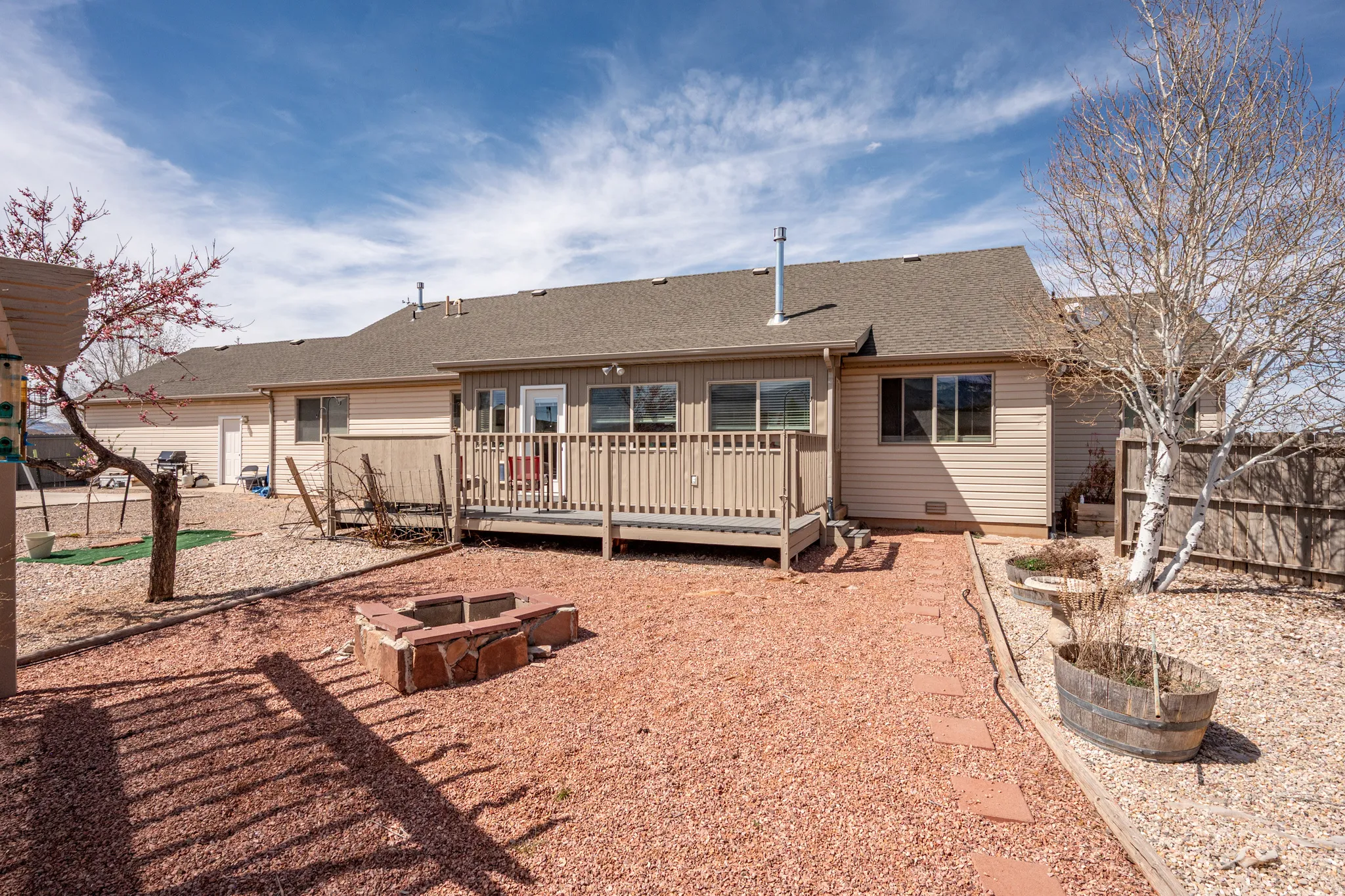 Rear view of property with roof with shingles, a deck, and an outdoor fire pit