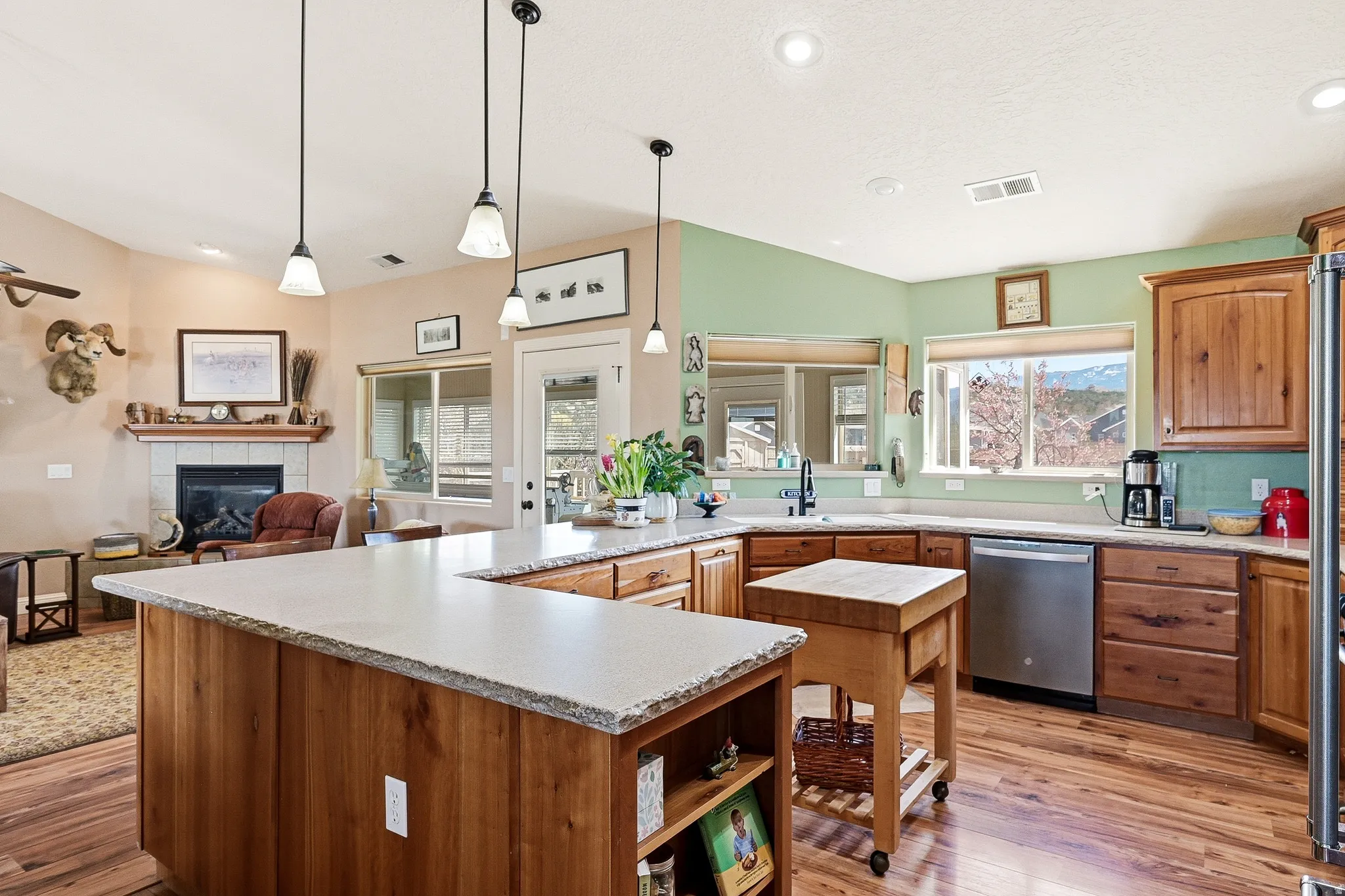 Kitchen featuring a tiled fireplace, a peninsula, dishwasher, wood finish cabinetry, and light wood-type flooring