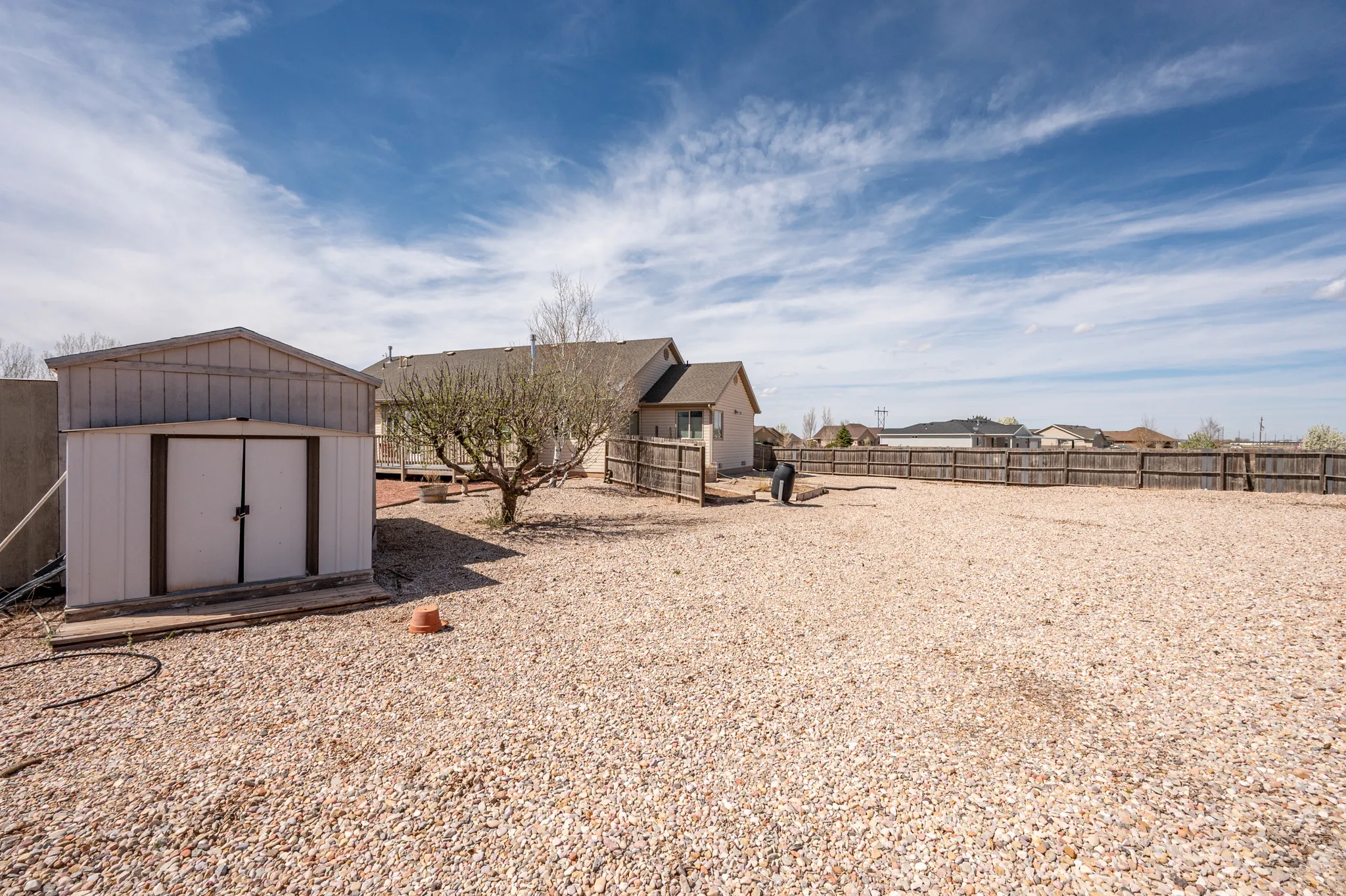 Fenced backyard featuring a storage unit and a residential view