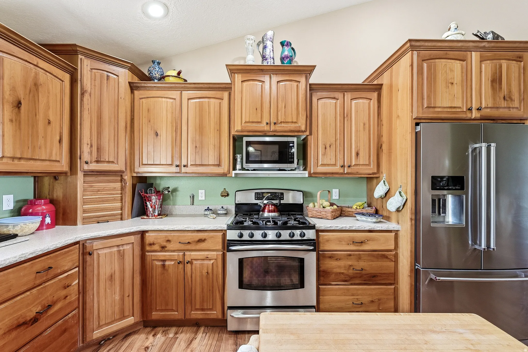 Kitchen with stainless steel appliances, light wood-style flooring, wood finish cabinetry, and vaulted ceiling