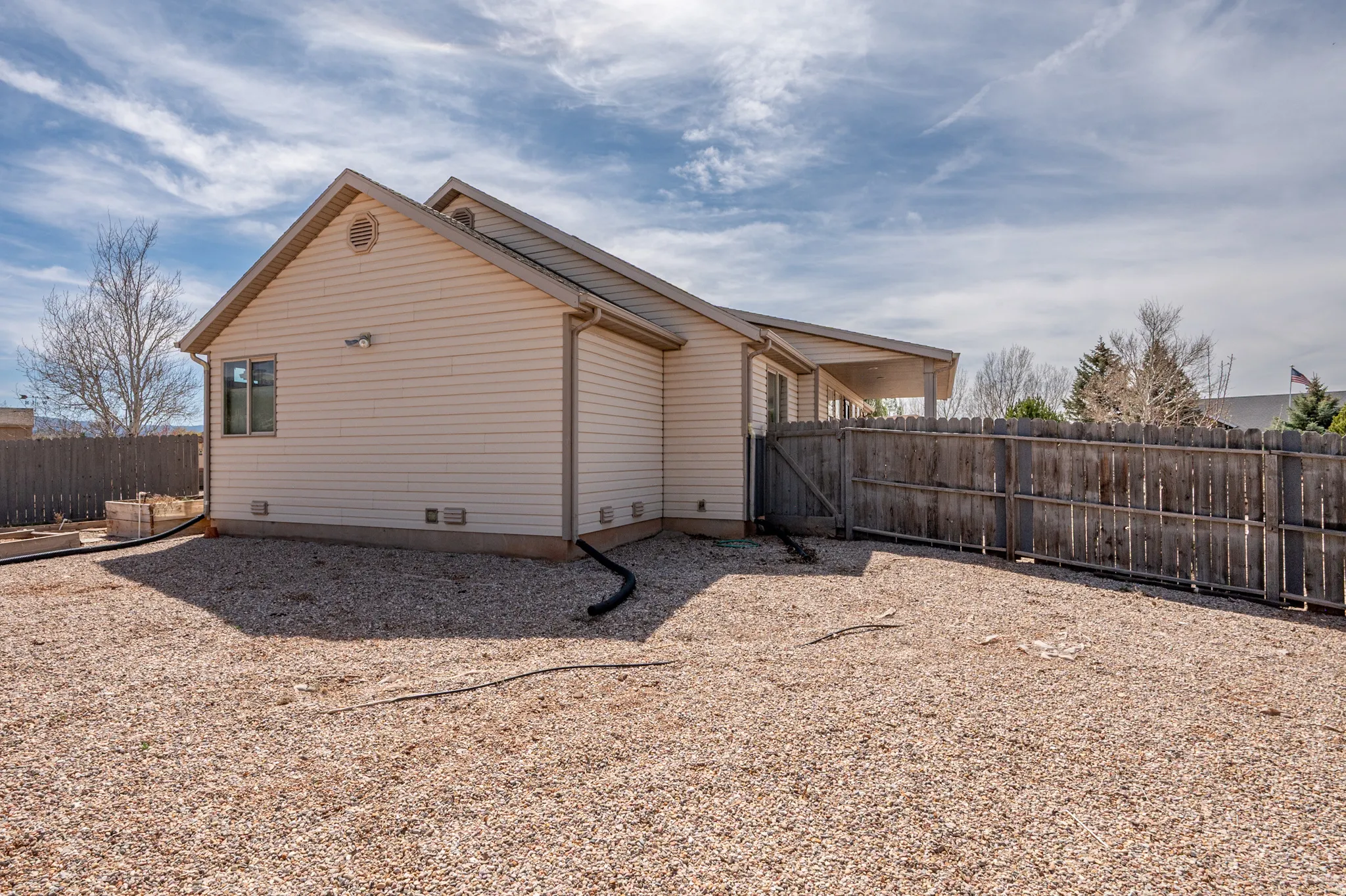 View of side of home with a fenced backyard and a gate