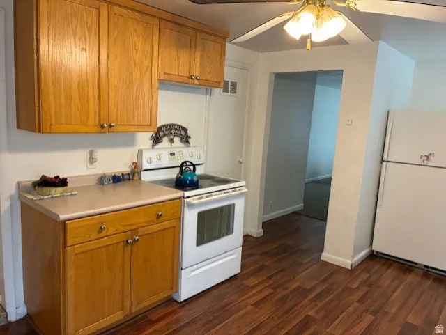 Kitchen featuring white appliances, a ceiling fan, light countertops, dark wood-type flooring, and wood finish cabinets