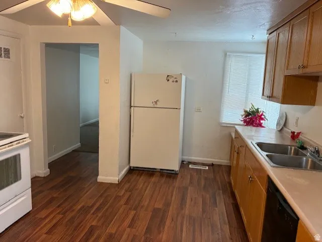 Kitchen with white appliances, light countertops, dark wood finished floors, and ceiling fan