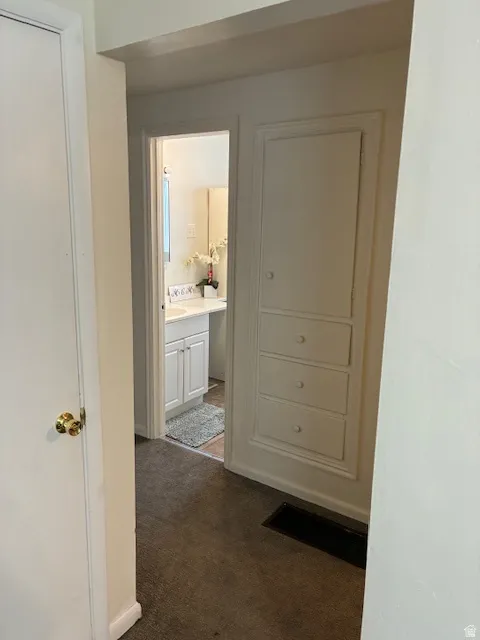 Hall featuring dark colored carpet