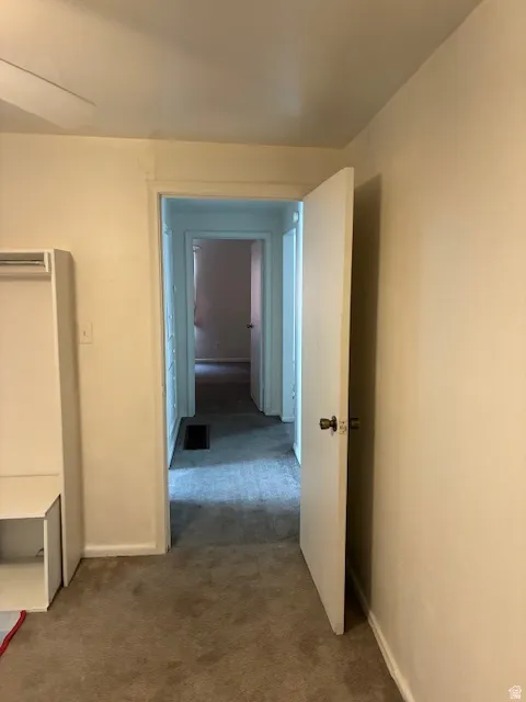 Hallway with dark colored carpet and baseboards