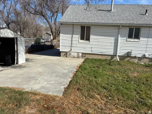 View of side of property featuring roof with shingles and a shed