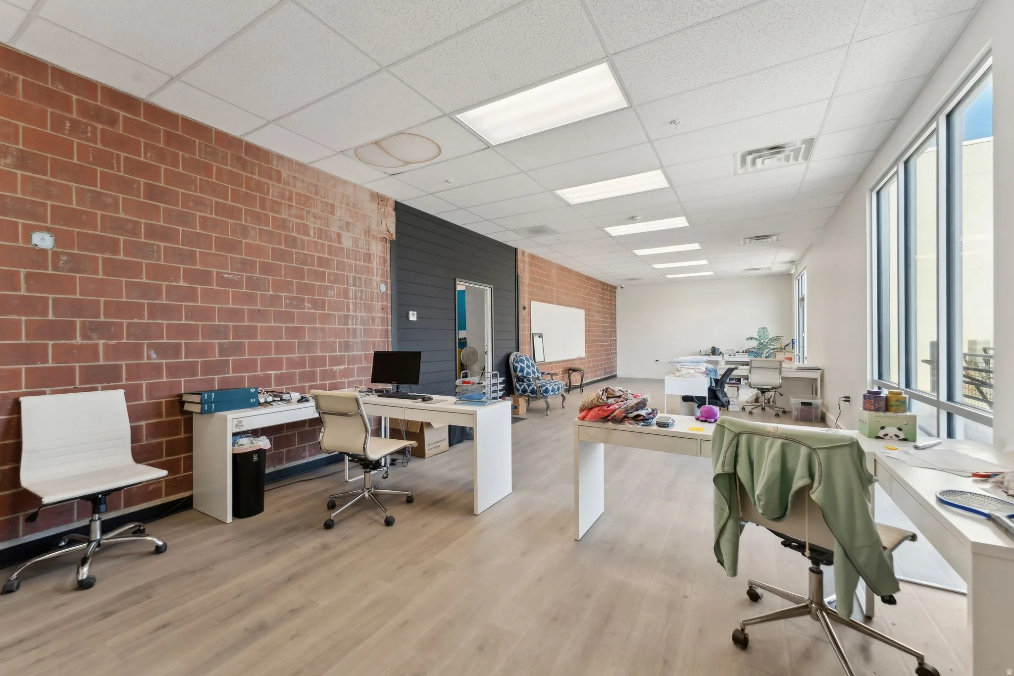 Office space featuring a paneled ceiling and brick wall