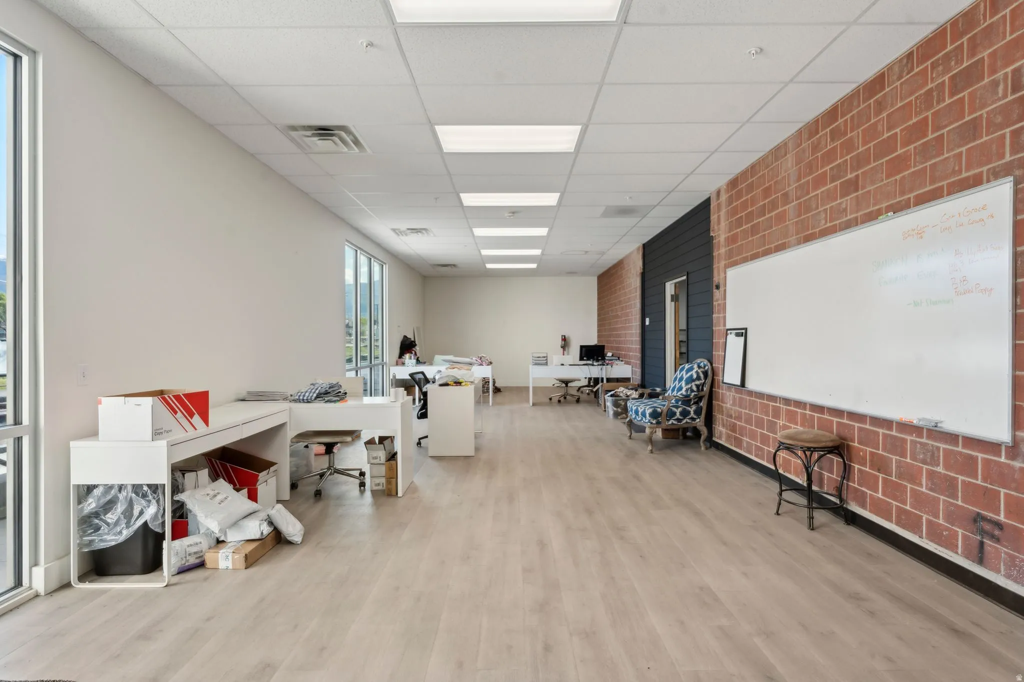 Office space with a drop ceiling and brick wall