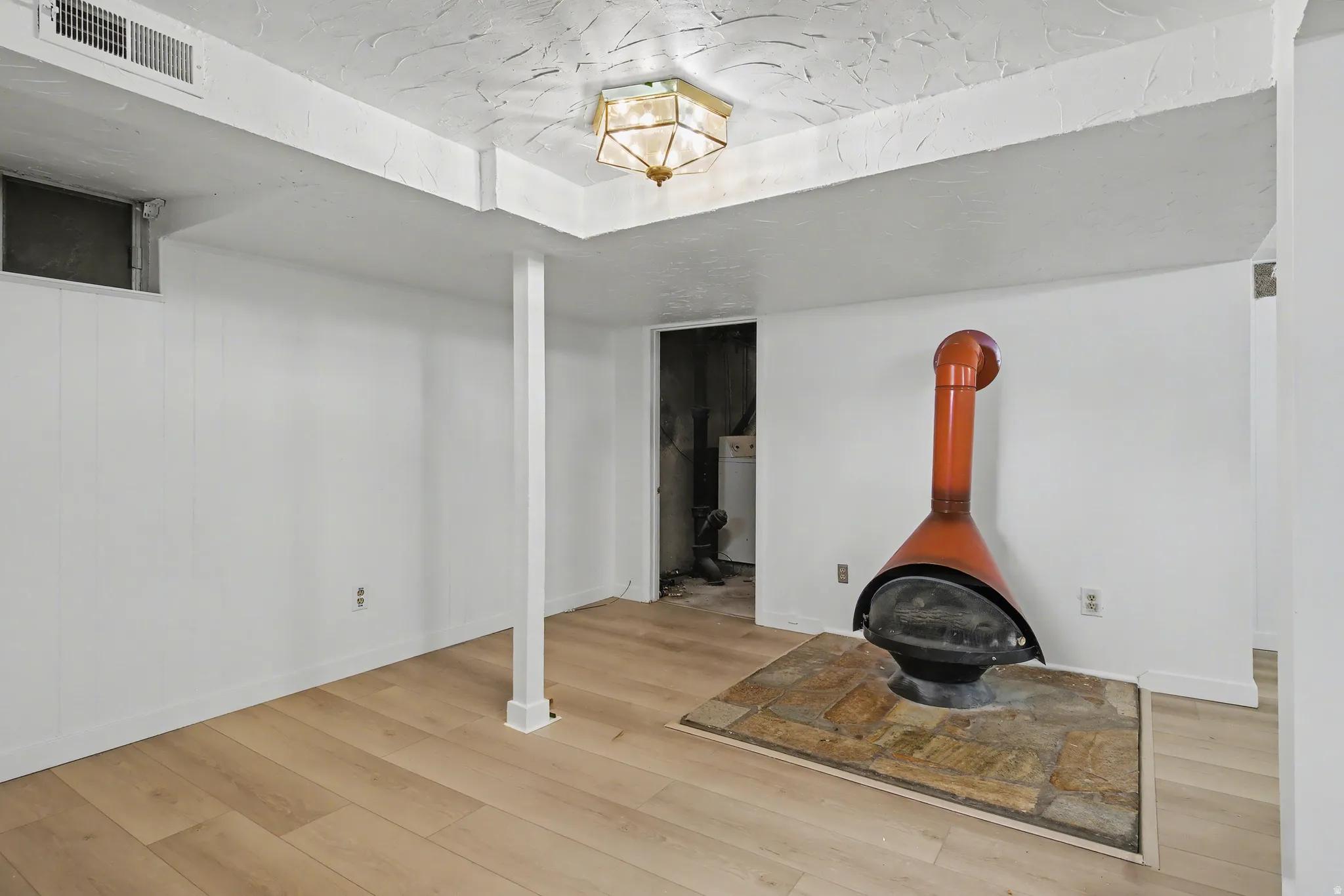 Finished below grade area featuring light wood-style flooring and a wood stove