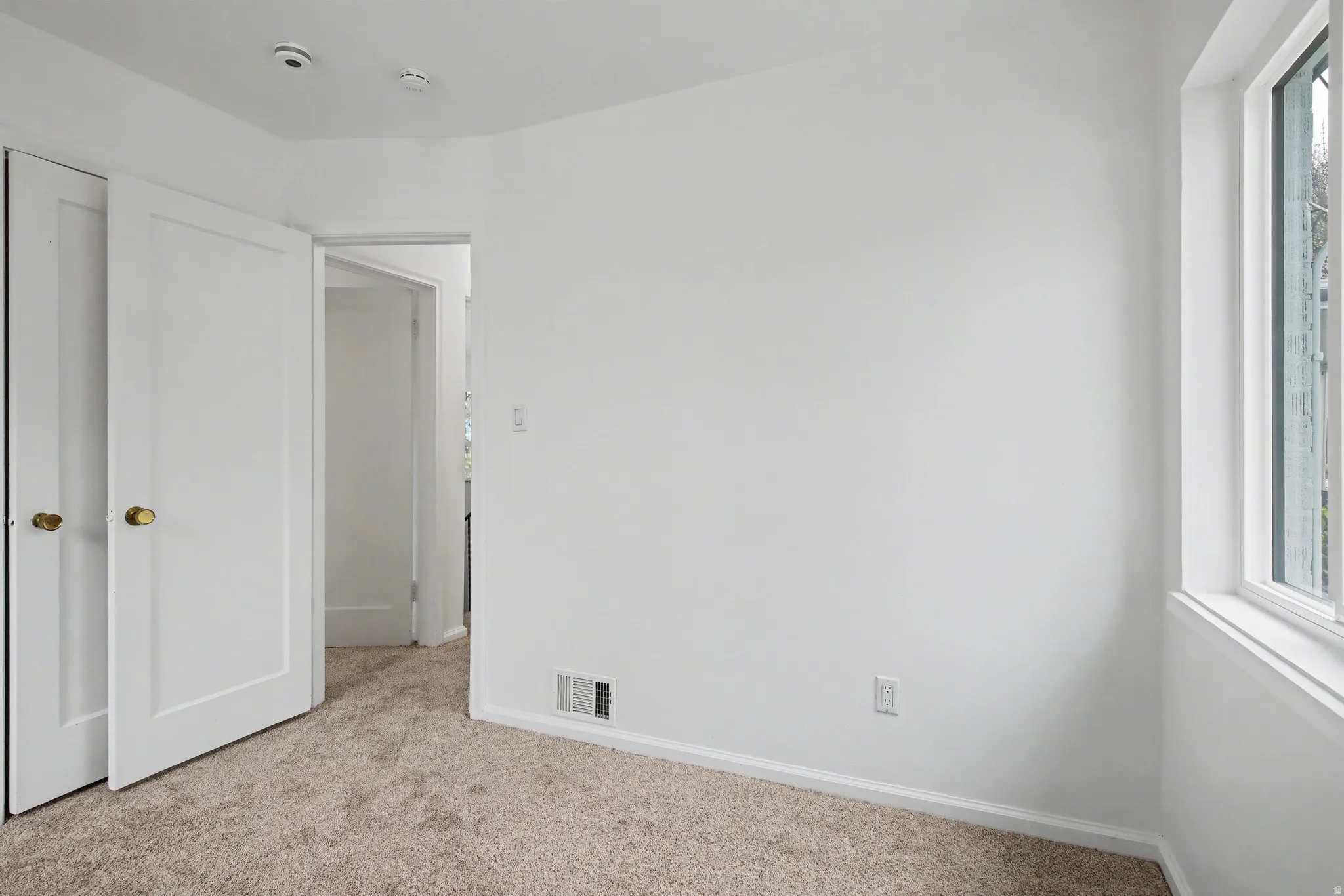 Unfurnished bedroom featuring light colored carpet and multiple windows