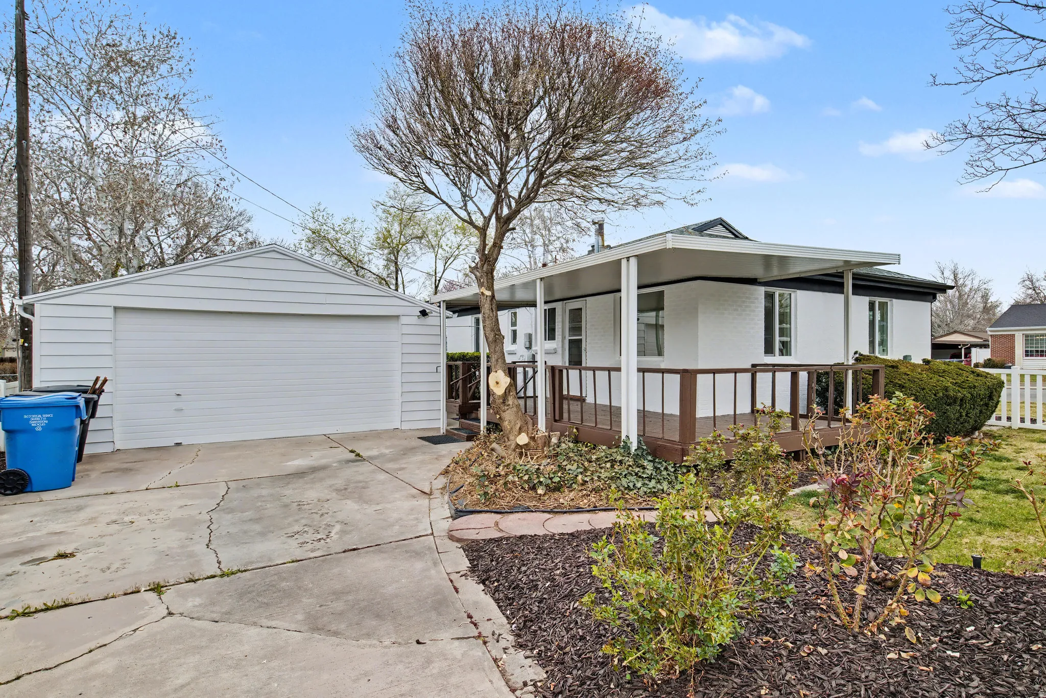 View of side of property with a garage, an outbuilding, brick siding, and a wooden deck