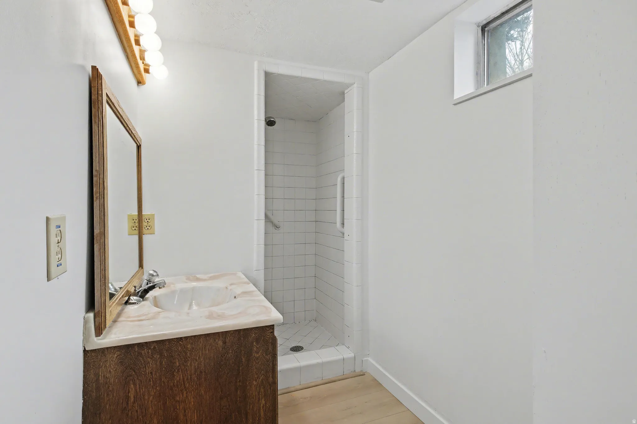 Full bath with vanity, light wood-type flooring, and a stall shower